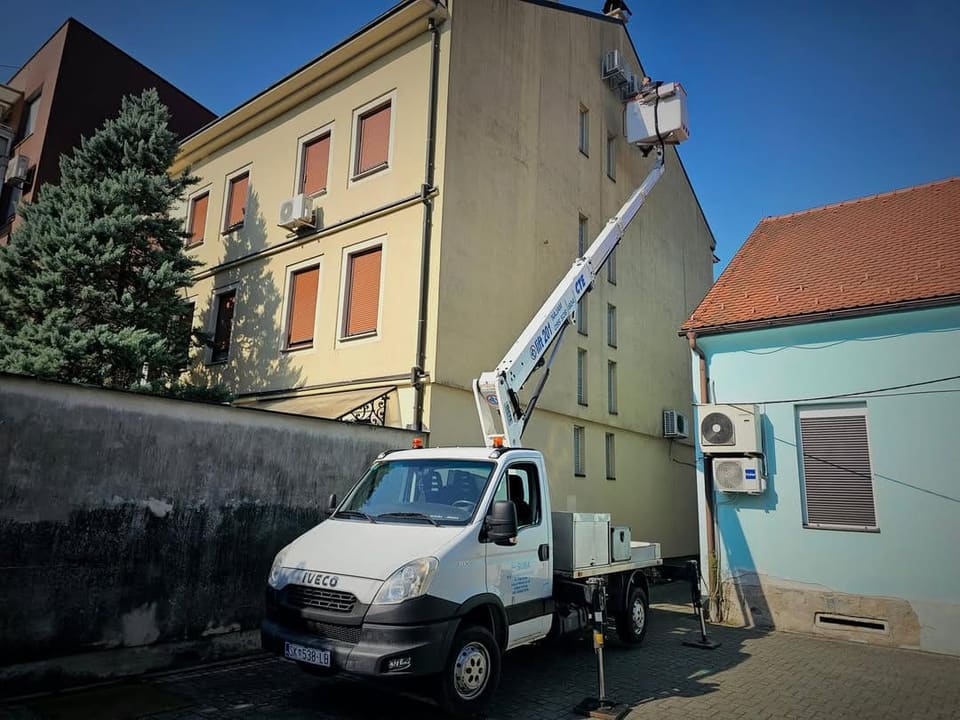 Autokošara s podignutom košarom uz fasadu zgrade