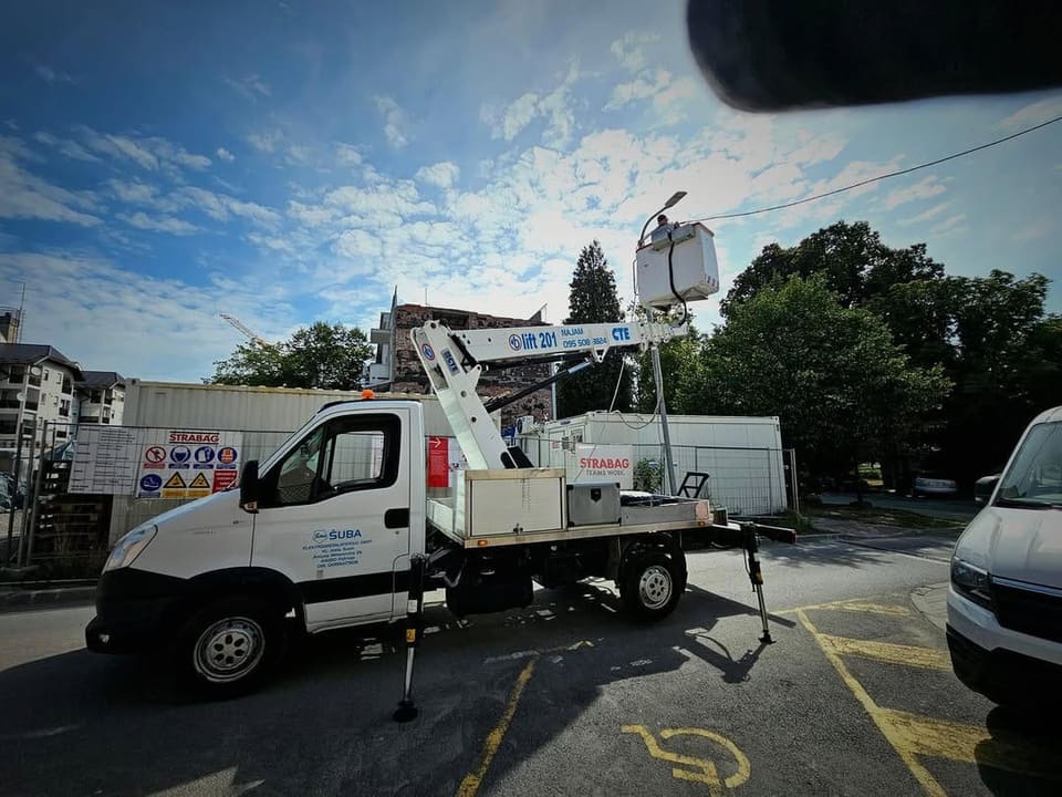 Vozilo s autokošarom i podignutom košarom na parkiralištu